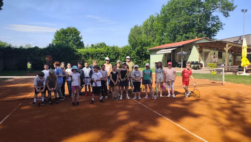 Kindergruppe mit Tennisschlägern auf dem Sandplatz beim Tenniscamp
