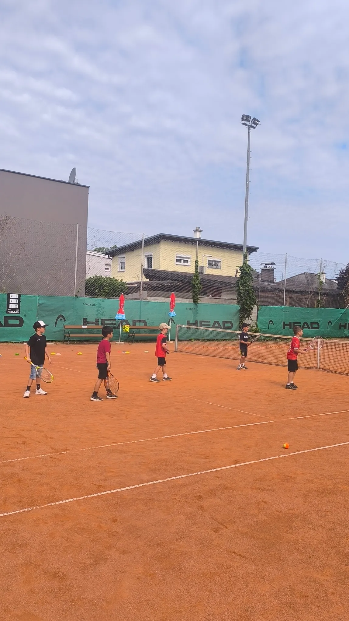 Kinder üben Tennis in der Gruppe auf dem Tennisplatz