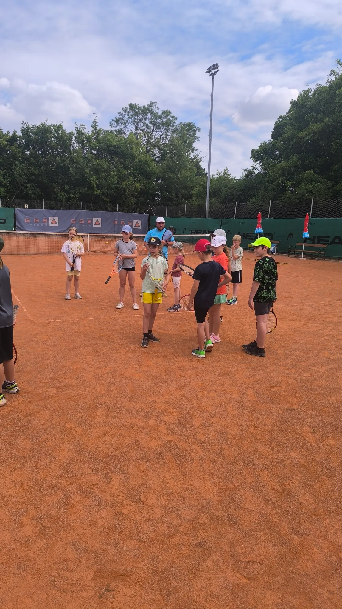 Kinder üben Tennis in der Gruppe auf dem Tennisplatz