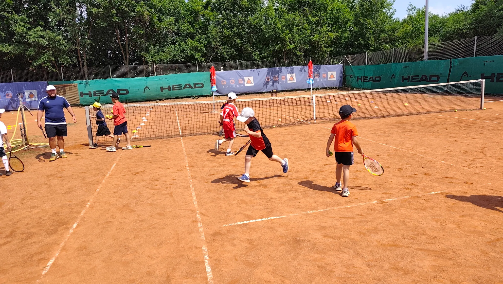 Kinder üben Tennisschläge beim Tenniscamp in der Gruppe